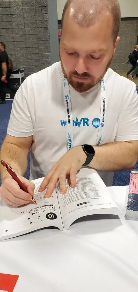 Gareth Walkom signing a copy of the book at the Plural Publishing meet and greet during the ASHA 2025 Convention.
